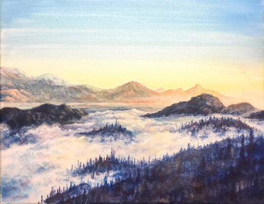 a sunrise scene of blue mountains covered in rising fog. in the distance are hazy orange mountains.